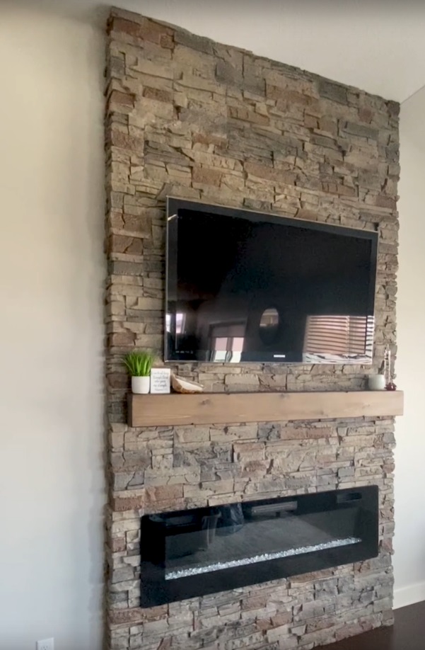 A Wall Mounted Electric Fireplace with a surround made of Kenai Stacked Stone panels.