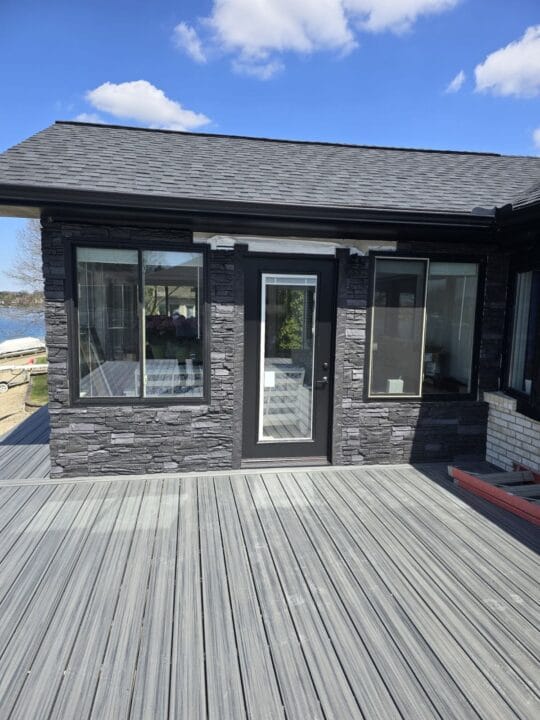 A siding project around a deck door using GenStone's Iron Ore Faux Stone panels.