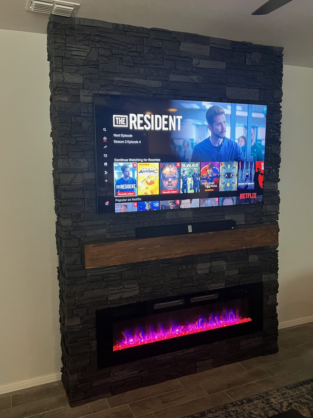 A wall mounted electric fireplace surround project made using GenStone's Iron Ore Stacked Stone.