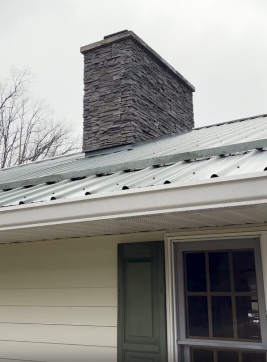 A DIY chimney on a roof made using GenStone's Kenai faux stone panels.