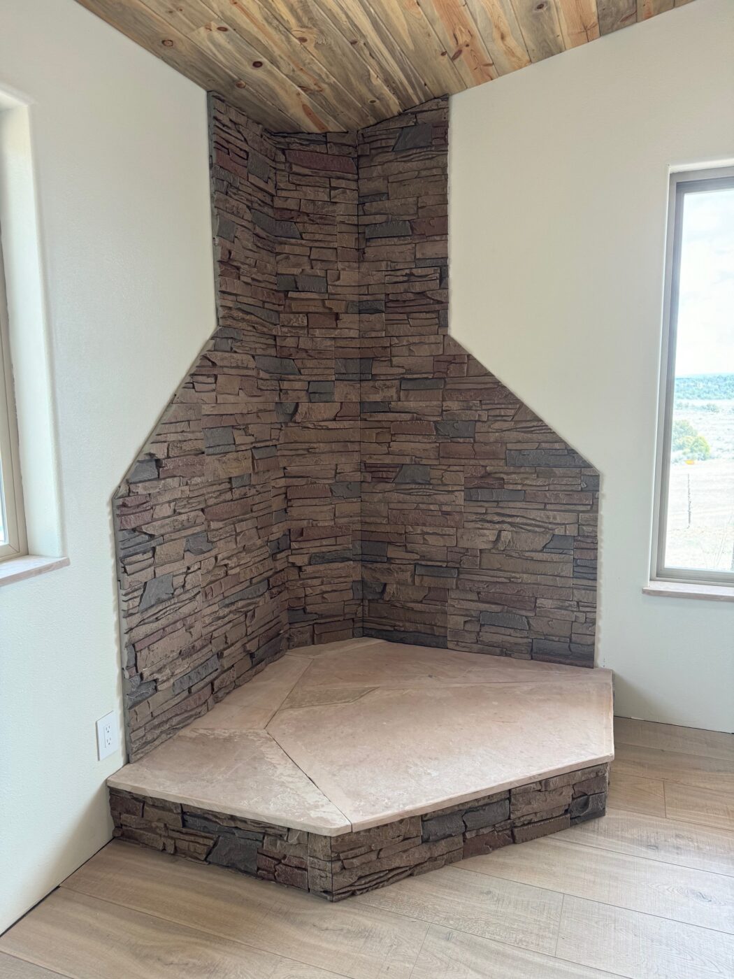 A DIY corner wood stove surround made using GenStone's Desert Sunrise Stacked Stone panels.